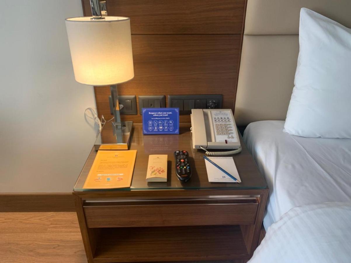 Jaypee Vasant Continental Hotel New Delhi Exterior photo A bedside table with a telephone, a lamp, a pen and a notepad